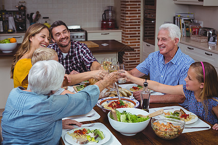 多代多代家庭在庆祝感恩节时举红白葡萄酒图片