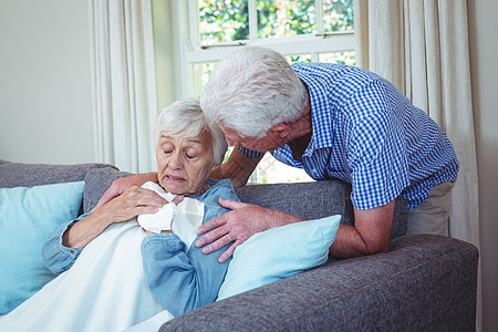 坐在沙发上跟生病的妻子说话的老人图片