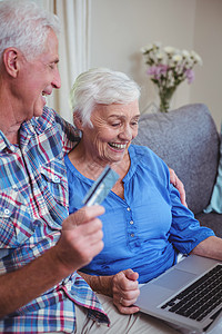使用信用卡和笔记本电脑对老年夫妇微笑图片