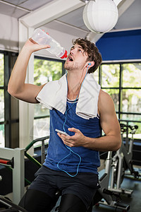 男人在旋转班级的饮用水和听音乐男性健身室身体体质沟通手机健身餐巾专注保湿图片