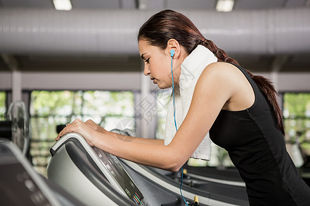 妇女在运动机上听音乐锻炼跑步机健身房娱乐身体训练专注器材听力健身室图片