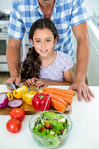 在厨房桌旁吃蔬菜 带女儿和父亲一起吃蔬菜图片