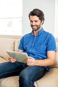 男人在家里坐在沙发上时使用数字石板图片