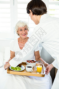 向老年妇女提供早餐的女照料者图片