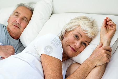 微笑的老女人和男人在床上放松的肖像图片