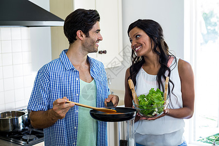 年青夫妇在厨房一起做饭男人通风罩女性烹饪女士台面准备食物情人微笑图片