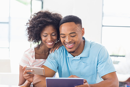 平板电脑和手机使用移动电话和数字平板电脑的幸福夫妇技术闲暇亲密感男性微笑卷发电话触摸屏沟通滚动背景