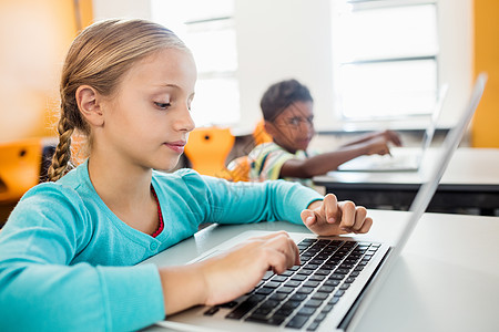 在课堂上使用笔记本电脑的小女孩侧边视图图片