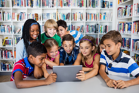 使用平板电脑 Pc 的学生前端视图微笑书架孩子们小学男性女孩们技术小学生学习笔记本图片