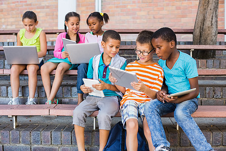 儿童在长凳上使用数字平板电脑和笔记本电脑女学生友谊女孩学校知识服装快乐微笑朋友喜悦图片