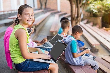 儿童坐在长椅上 使用笔记本电脑平板知识男生女性微笑学生技术沟通混血女孩图片