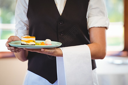 服务员拿着一个带蛋糕的盘子食品女性工作服务餐饮马甲零售毛巾行业美食图片