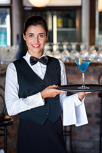 酒保拿着装满鸡尾酒杯的托盘餐巾微笑茶点酒吧女士酒保职业酒精女性制服图片