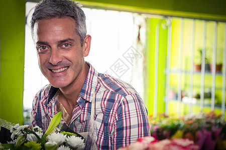 鲜花店里微笑的男花匠中心花艺职业植物服装花店服务商业花束失速图片