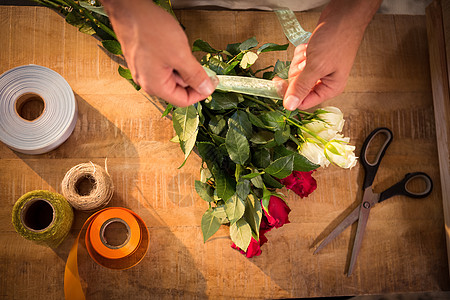 男花匠在一束花朵上绑多丝带剪刀花艺商业花园花束职业植物区系失速零售图片