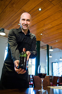 拿着一瓶红酒的服务员商业微笑咖啡店工作酒店服务玻璃食品瓶子行业图片