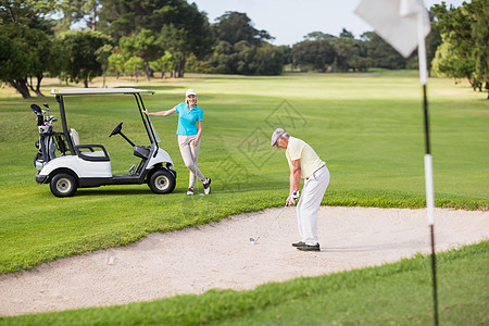 由女人在沙地上玩高尔夫球图片