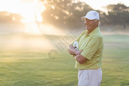 快乐高尔夫球手的横穿双臂的肖像活动手套快乐高尔夫男人幸福微笑棒球帽老年服装图片