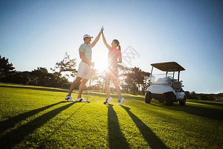 快乐的高尔夫球员夫妇击掌活动成功生活方式高尔夫球享受运动员阴影男人假期团结图片