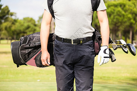 身穿高尔夫球袋的人的中流体晴天高尔夫手套生活方式运动员爱好假期阳光休闲活动图片