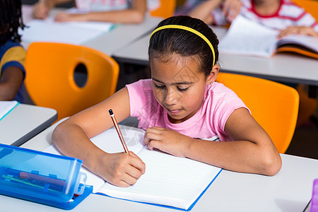 女孩在笔记本上写字发带女性同学们小学学校童年铅笔专注班级混血图片