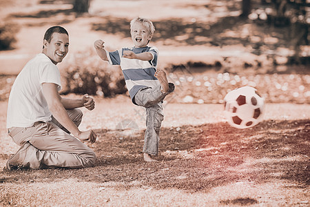 夏天父亲和儿子在足球比赛中一起踢球游戏孩子微笑场地运动公园男生眼睛男人绿色图片