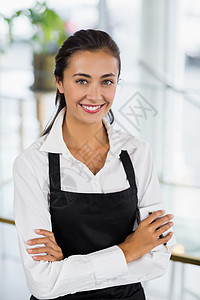 微笑的女服务员站在手举着横穿双手的肖像咖啡店柜台服务职业快乐工人款待酒店工作双臂图片