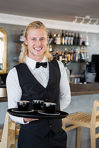在餐馆里端着咖啡杯托盘的服务员微笑服务饮料职业餐厅食品零售酒店工作男性图片