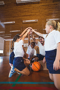 体育教师和在篮球法庭上成手架的学校儿童女学生瞳孔女孩指导木地板男人运动快乐小学混血图片