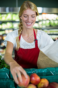 在超市用纸袋包装水果的女工作人员图片