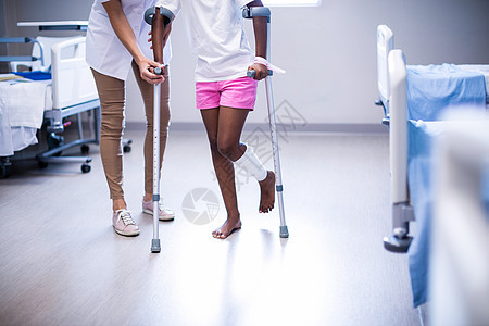 女医生协助女孩在病房中用拐杖走路残障疼痛医院医学事故保健依赖服装专注专家图片
