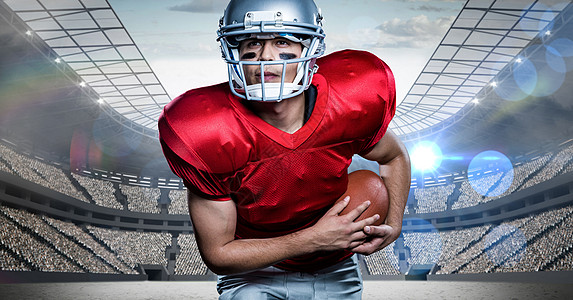 美国足球运动员持橄榄球与体育场背景比对的橄榄球面漆观众战略运动竞技场战绘运动服安全聚光灯论坛图片