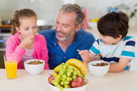 父亲和孩子在厨房吃早餐时微笑桌子女性闲暇服装营养快乐家庭麦片女孩休闲图片