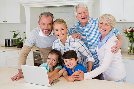 幸福家庭站在厨房的肖像亲密感互联网快乐儿子女士女孩微笑技术电脑笔记本图片