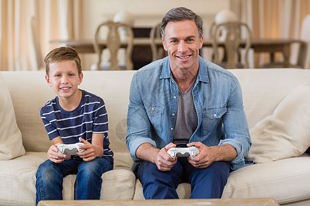 父亲和儿子在客厅玩电子游戏图片