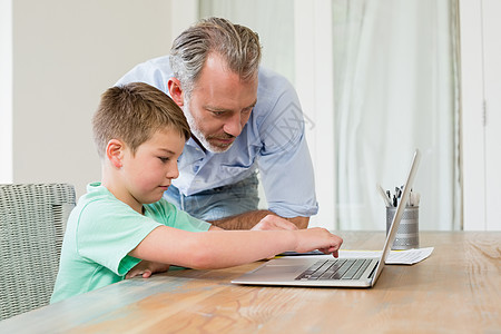 父亲和儿子在书桌上使用笔记本电脑生活感情男生房子童年技术男性孩子桌子服装图片