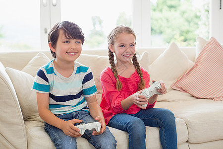 在客厅里玩电子游戏的兄弟姐妹家庭生活闲暇坐垫愁云安慰快乐住所家庭女孩男性图片