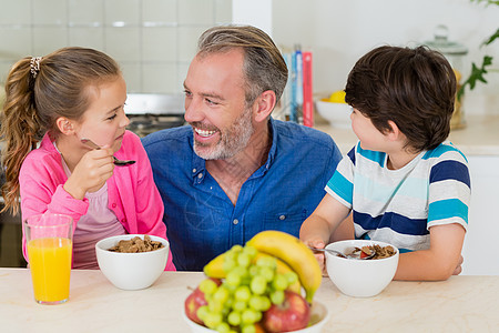 父亲和孩子在厨房吃早餐时微笑家庭勺子服装房子住所麦片快乐休闲男生营养图片