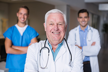 带着双手站在十字路口的微笑的医生的肖像医疗电脑老年制服双臂沟通专家技术触摸屏诊所图片