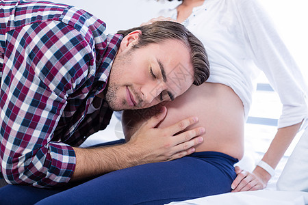 男人在病房里听孕妇肚子的图片