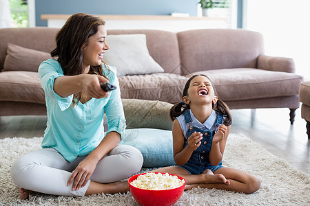在客厅吃爆米花时 母亲和女儿在电视上看图片
