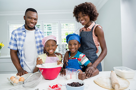 父母和孩子在家厨房做饭时在厨房准备食物快乐母亲儿子女士滚板家庭生活家庭台面面团女儿图片