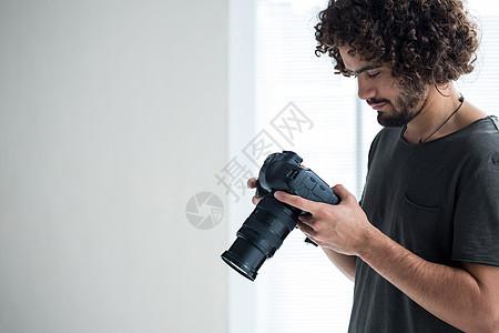 男性摄影师翻阅数码相机中拍到照片的男摄影师工作室工作魅力休闲现实电子专注相机活力服装图片