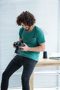 摄影师审查在数码相机中拍下的照片工作室相机休闲技术男人单反男性服装商业活力背景图片