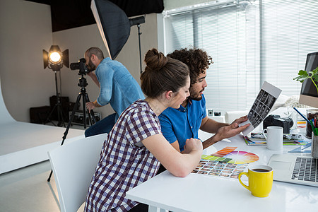 摄影师小组在办公桌一起工作照片笔记本文档现实互动技术单反艺术家讨论平面设计师图片