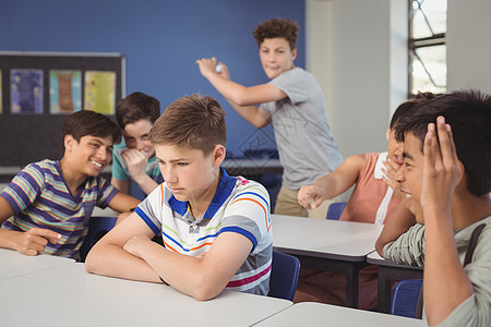 学校朋友在课堂上欺凌一个悲伤的男孩桌子女学生女孩青少年技术专注青春期男性青年双臂图片