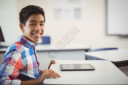 书桌上有数码平板电脑的中学生男生快乐服装男性智力知识学校青春期混血青年图片
