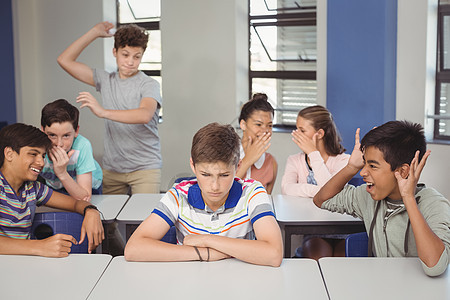 学校朋友在课堂上欺凌一个悲伤的男孩沟通青春期同学混血八卦专注休闲中学女学生悲哀图片