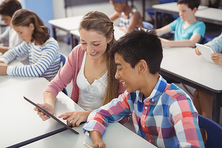 学生在课堂上使用数字平板电脑和笔记本电脑的学生快乐知识技术混血男性友谊女性青春期青少年学校图片
