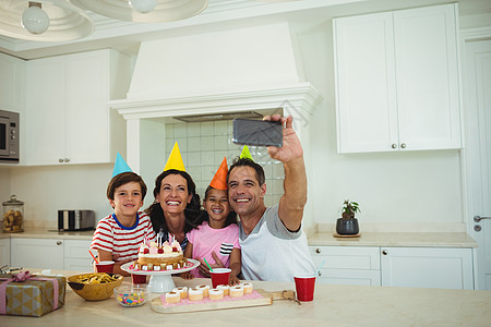 在庆祝生日时 快乐的一家人拿自拍服装回忆盘子果汁照片杯子派对休闲男人沟通图片